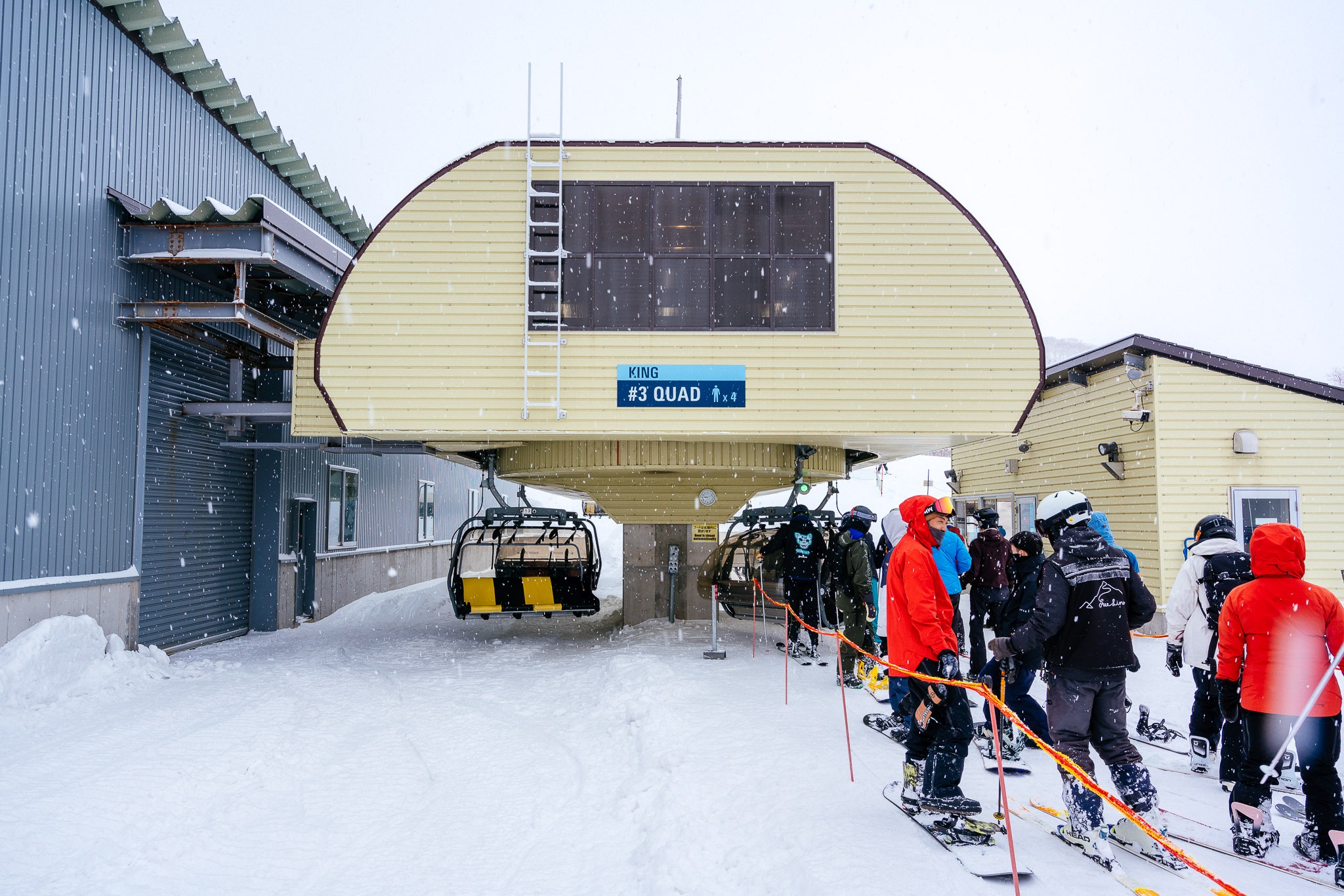 Snowboarders queuing up to ride King Quad chairlift in Niseko.