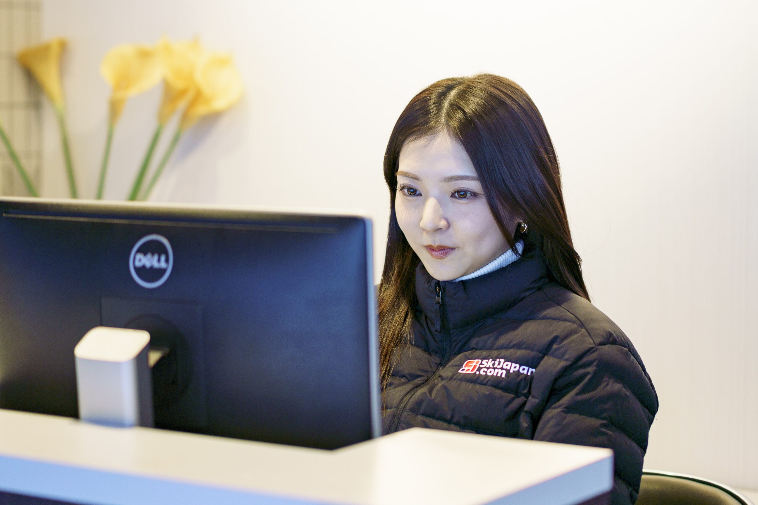 A Ski Japan member of staff using a computer at the front desk.