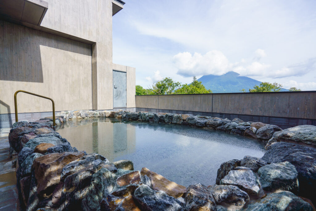 An outdoors hot spring bath with Mount Yotei in the background