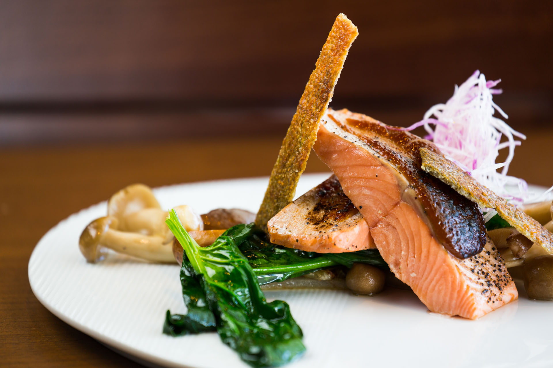 chinese-new-year-niseko-2 Gourmet grilled salmon dish with mushrooms and greens on white plate.