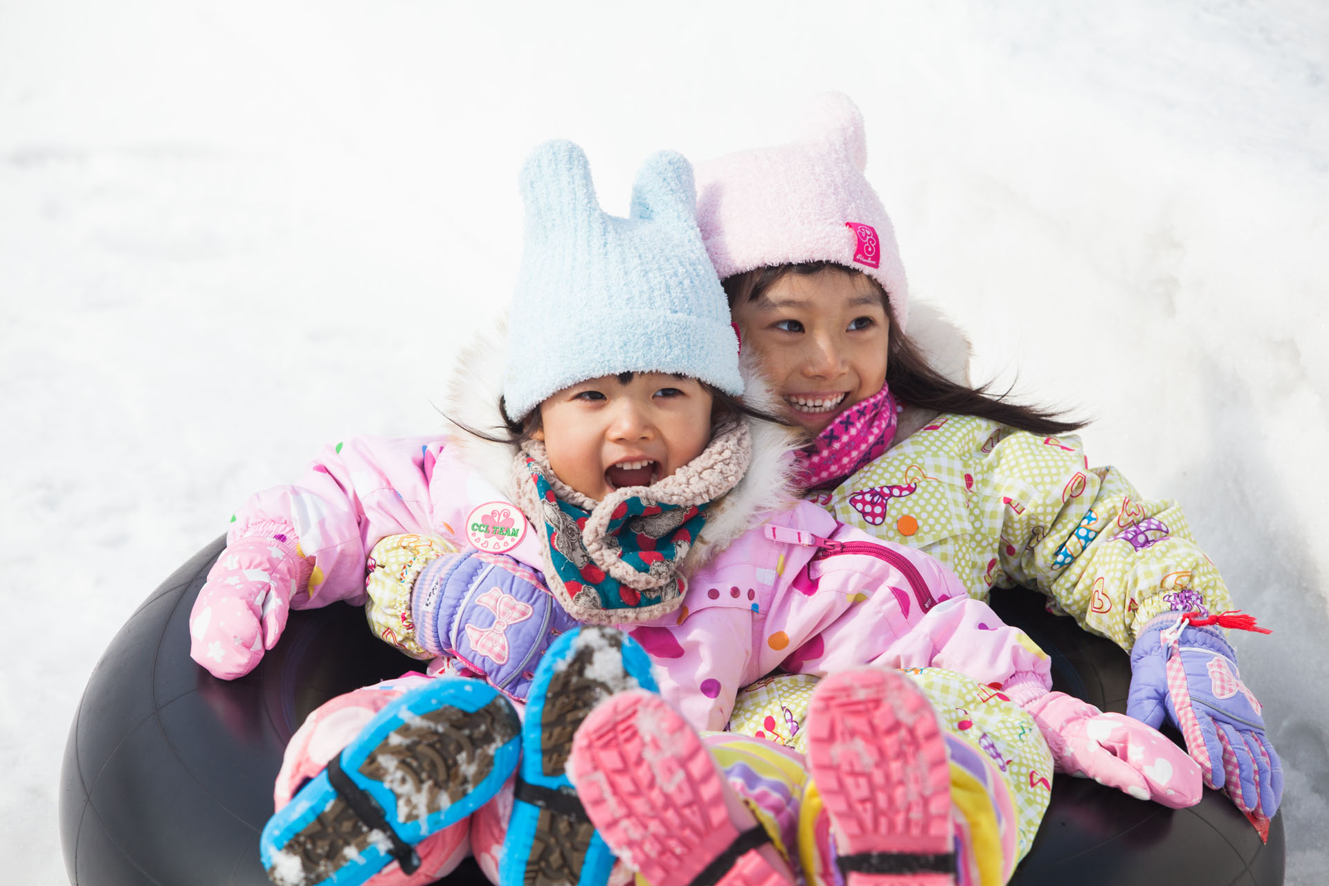 chinese-new-year-niseko-5 Two children smiling in colorful snowsuits while playing in the snow.
