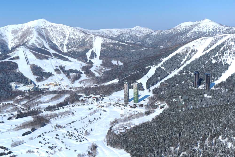 japans-best-ski-resorts-6 Aerial view of Tomamu ski resort with tall hotels, snow-covered trails, and forested peaks.