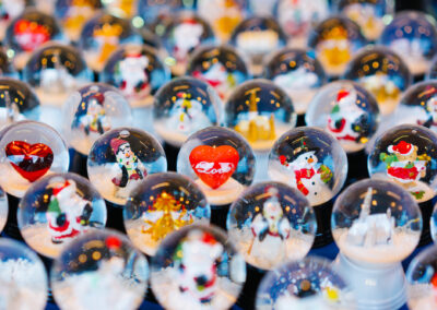 A vibrant assortment of festive Christmas snow globes, featuring figures like Santa, snowmen, and a red heart.