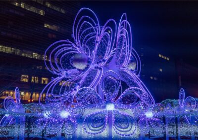 A large purple and white floral light sculpture glows at night during the Sapporo White Illumination event in Odori Park, Japan.