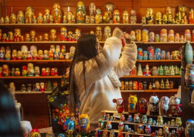 A lady is browsing a shop filled with extensive shelves of colorful, traditional and animal-themed Matryoshka nesting dolls at Sapporo Christmas Market.