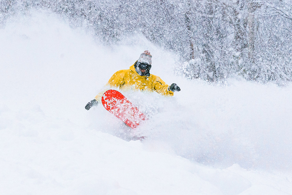 A snowboarder doing a big powder turn, for Niseko webcams page